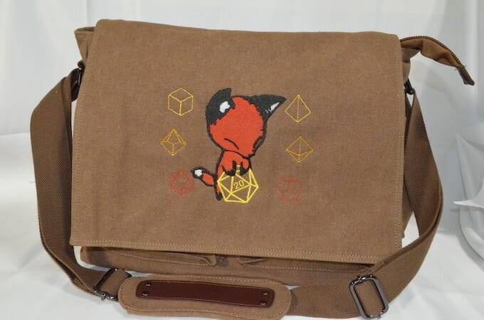 Uber Dungeon - fox holding a dice decorates a messenger bag
