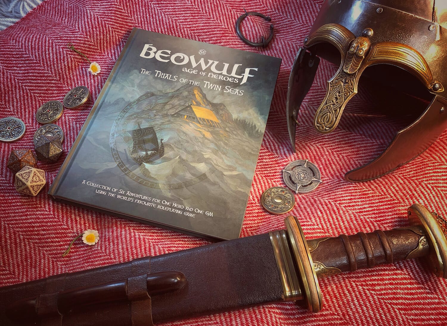 Beowulf book lays on red rug with coins, a helmet and short sword nearby