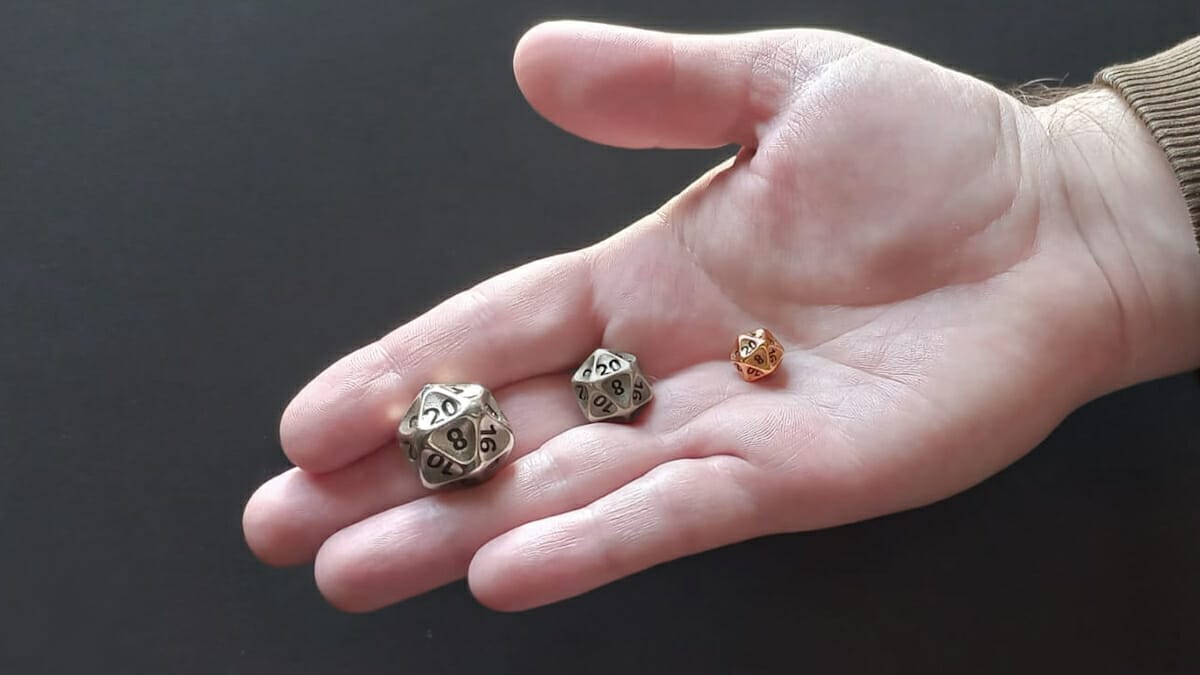 Three sizes of d20 in a hand